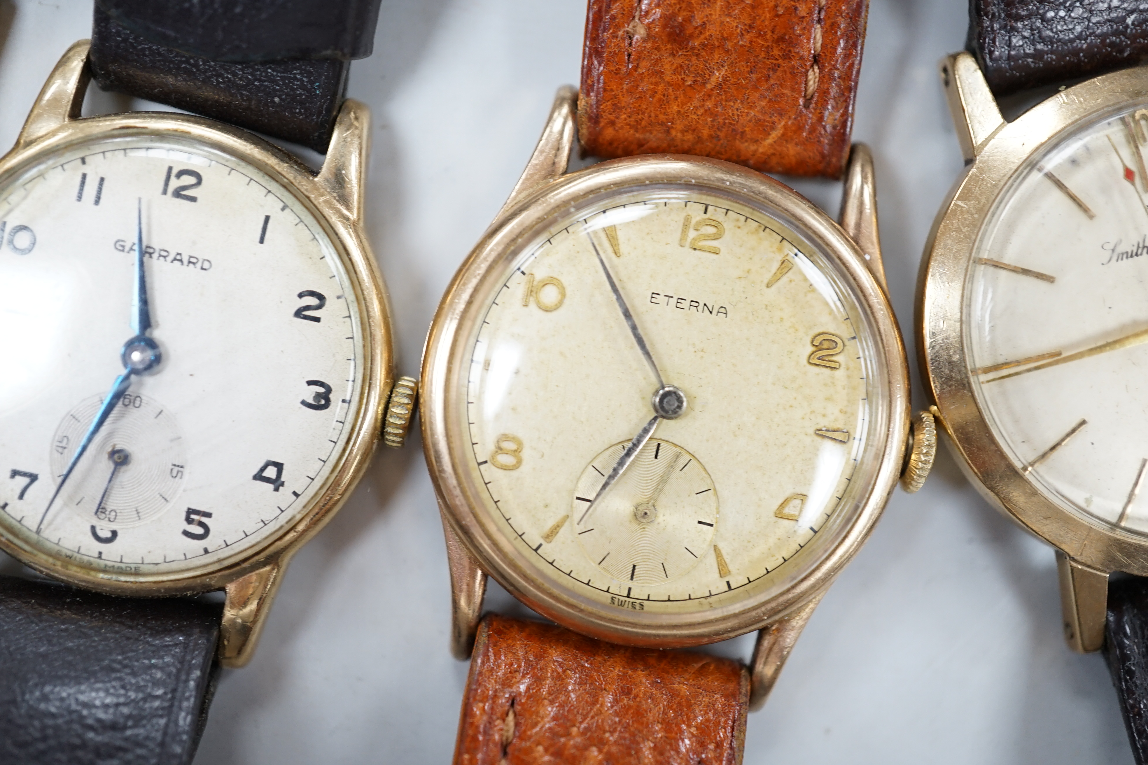 Two gentleman's 9ct gold manual wind wrist watches, retailed by Garrards, both with engraved inscription and two other 9ct gold wrist watches including Eterna.